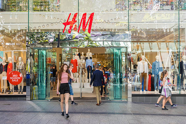 Young woman walking out of H&M store in Brisbane Brisbane, Australia - September 26, 2016: View of a young woman walking out of H&M store in Brisbane. H M is a well-known international fashion retail corporation. h and m stock pictures, royalty-free photos & images