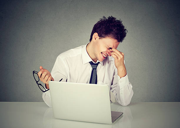istock Tired man rubbing eye sitting at table with laptop 622051788