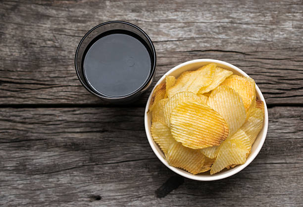 kartoffelchips in schüssel mit cola auf holztischhintergrund. - potato chip stock-fotos und bilder