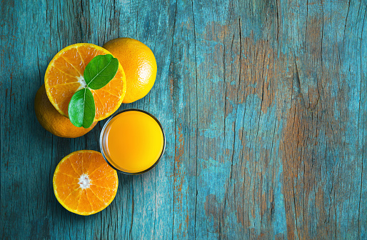 Glass of orange juice from above on blue grunge vintage wood table. Empty ready for your orange juice, fruit product display or montage.