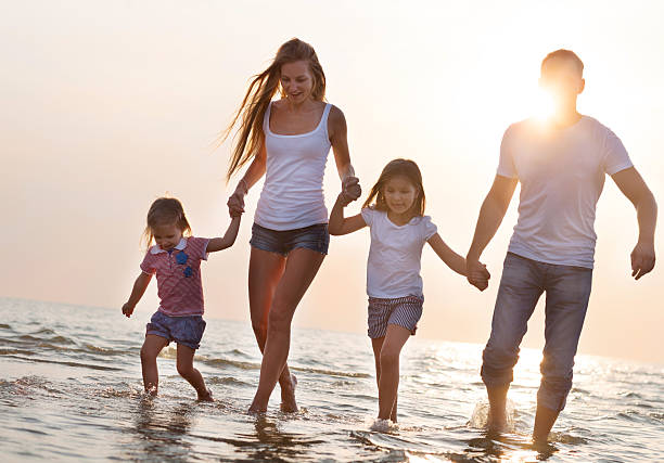 istock Happy young family having fun running on beach at sunset 622064816