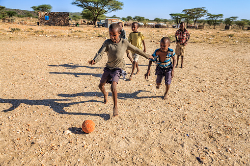 Barefoot African children  from Samburu tribe playing football in the village, East Africa, Kenya, East Africa. Samburu tribe is one of the biggest tribes of north-central Kenya, and they are related to the Maasai.