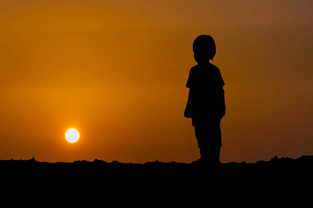 istock The silhouette of young boy standing with looking sunset 622065918