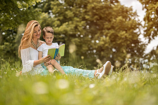 istock Smiling mother reading a book to her son in nature. 622067646