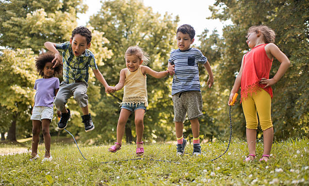 Group of playful kids having fun while skipping jump rope. Happy children having fun in the park while playing with jumping rope. jump rope stock pictures, royalty-free photos & images