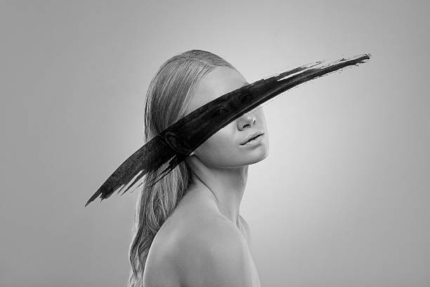 Black and white studio shot of an attractive young woman conceptualizing beauty with an artistic smear