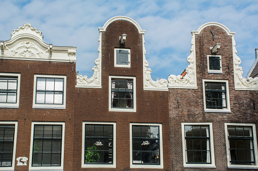 Amsterdam canal house facades with a blue sky in the background during summer.