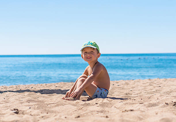 istock Smiling little baby boy sitting and playing with the sand 622077100