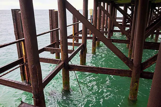 fragment construction. metal posts, rusty metal pier, sea water green