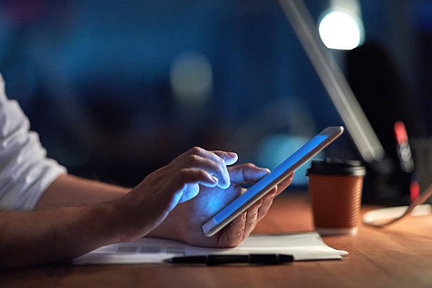 Smashing the deadline with smart technology Cropped shot of a businessman using a digital tablet at night in an office using digital tablet stock pictures, royalty-free photos & images