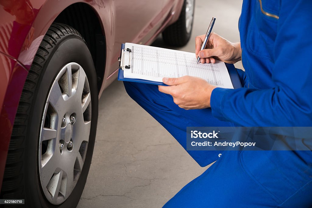 Mechanic Examining Car Wheel Young Mechanic Writing On Clipboard White Examining Car Wheel Car Stock Photo