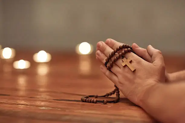 Cropped shot of a man holding a rosary and praying