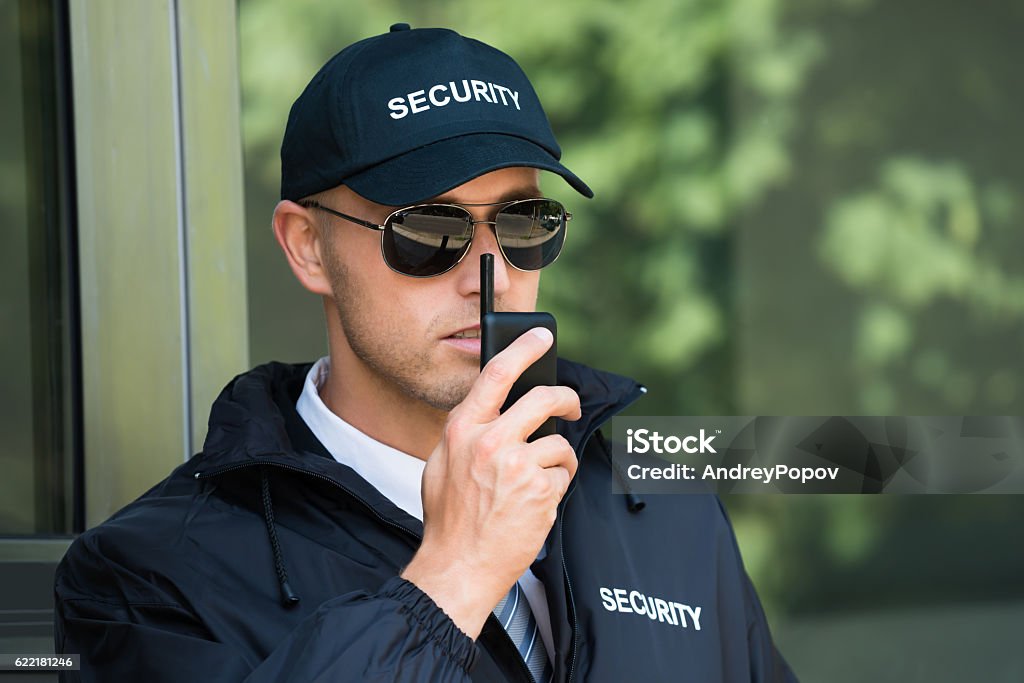 Young Security Guard Talking On Walkie-talkie Portrait Of Young Security Guard Talking On Walkie-talkie Security Guard Stock Photo