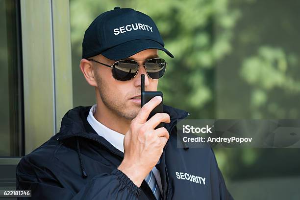 Young Security Guard Talking On Walkietalkie Stock Photo - Download Image Now - Security Guard, Security, Officer - Military Rank