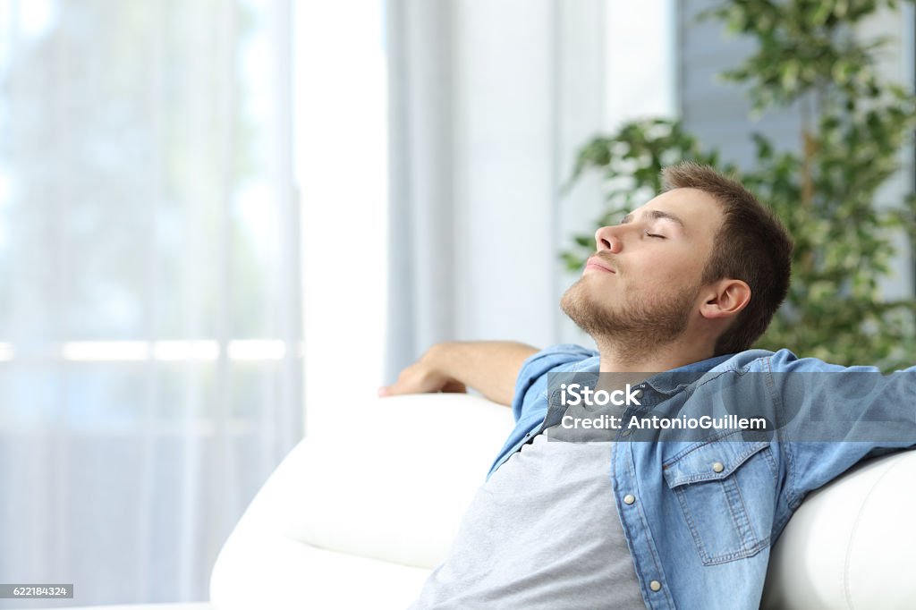 Hombre descansando en un sofá en casa - Foto de stock de Hombres libre de derechos