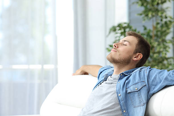 Man resting on a couch at home Portrait of a casual tired man resting sitting on a couch at home tranquil scene stock pictures, royalty-free photos & images