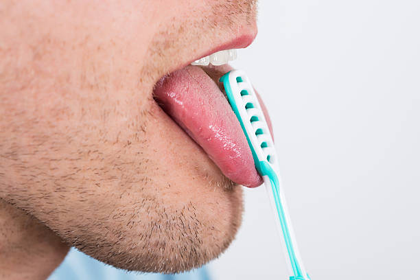 Man Cleaning Her Tongue Close-up Of Young Man Cleaning His Tongue With Scraper scraping stock pictures, royalty-free photos & images