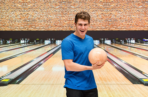 Smiling man playing bowling ball
