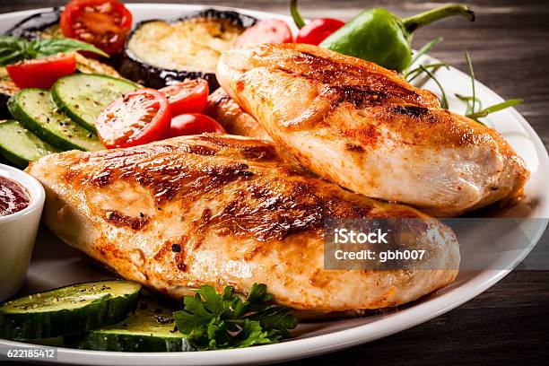 Fried Chicken Fillets And Vegetables On Wooden Background Stock Photo - Download Image Now