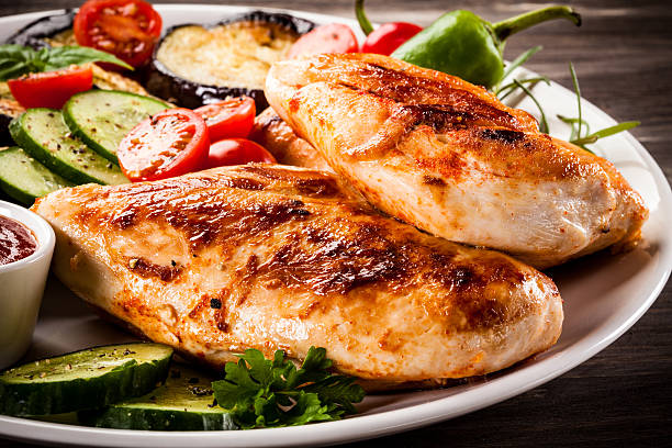 обжаренное куриное филе и овощи на деревянном фоне - chicken breast стоковые фото и изображения