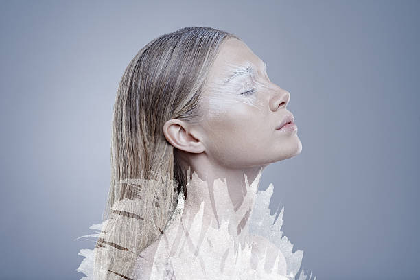 Portrait of a young Caucasian woman in feathers with multicolor highlights on her face.