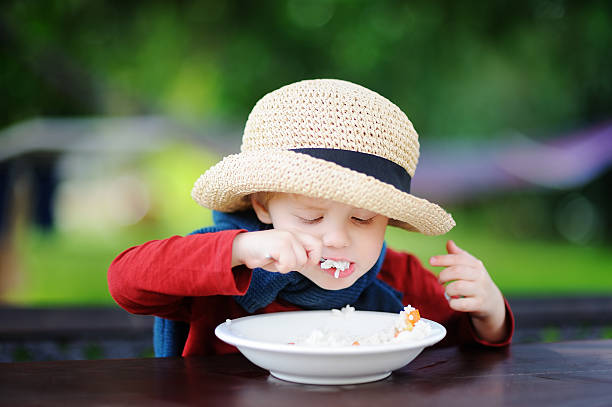 menino fofo comendo cereal de arroz ao ar livre - cereais de pequeno almoço - fotografias e filmes do acervo
