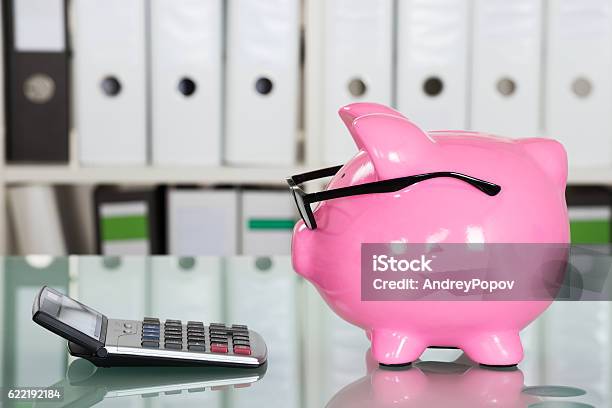 Piggybank Wearing Eyeglasses And Calculator On Desk Stock Photo - Download Image Now