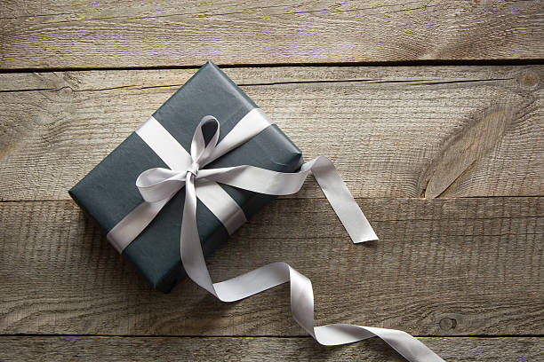 Gift box wrapped in black paper with ribbon on board. Gift box wrapped in black paper with silver ribbon on wooden surface. coupon photos stock pictures, royalty-free photos & images