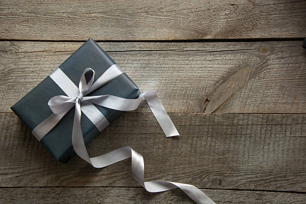 istock Gift box wrapped in black paper with ribbon on board. 622192520