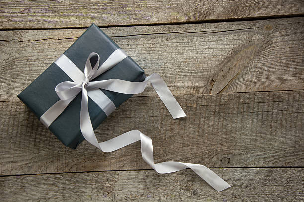 istock Gift box wrapped in black paper with ribbon on board. 622192728
