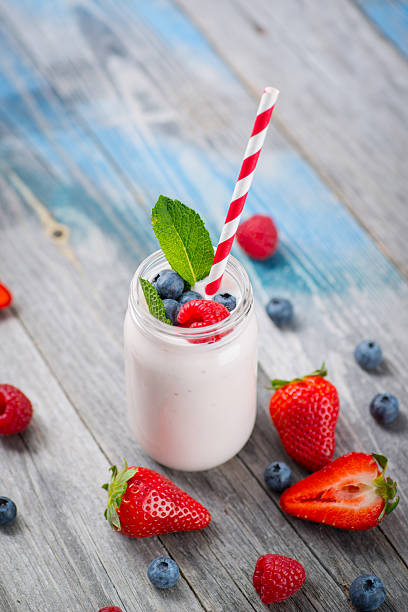 Jar with drinking yogurt, berries and straw on rustic wooden table