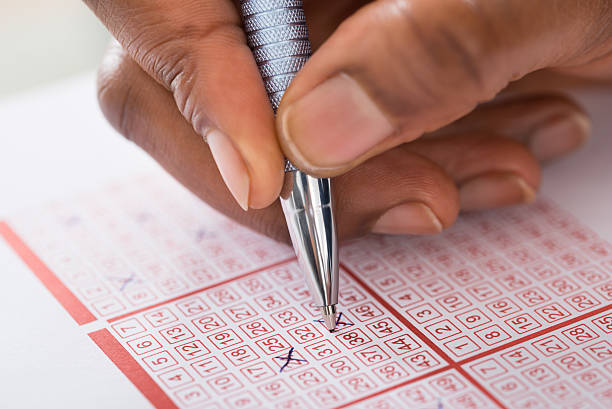 istock Person Marking Number On Lottery Ticket With Pen 622200154