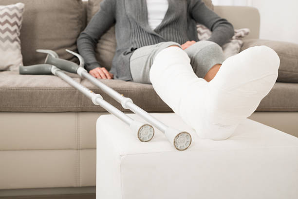 Woman With Plastered Leg Sitting On Couch Close-up Of Woman With Plastered Leg Sitting On Couch At Home orthopedic cast stock pictures, royalty-free photos & images