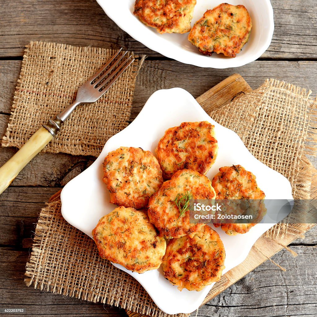 Fried fish cakes on a plate Fried fish cakes on a plate and on old wooden background. Cutlets cooked from salmon meat. Delicious and nutritious lunch or dinner recipe Fish Cakes Stock Photo