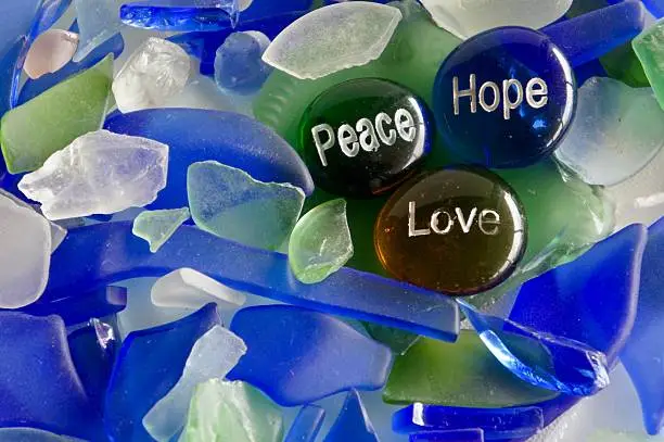 Stones with peace, hope, and love on a background of seaglass.