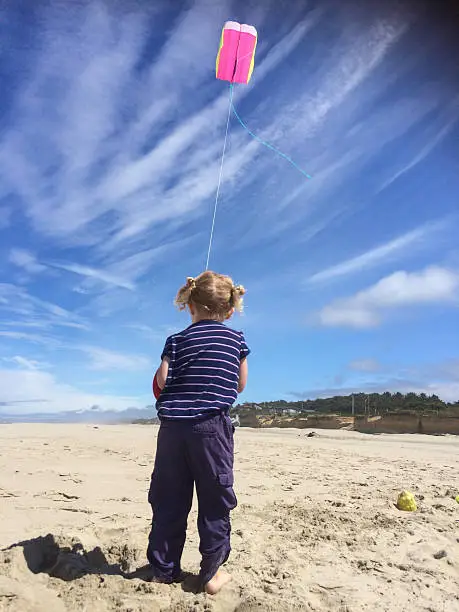 A little girl enjoying kite flying on a nice windy summer day on the Coast.  