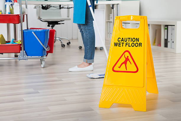 istock Female Janitor Mopping Wooden Floor With Caution Sign 622211844
