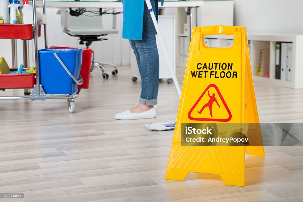 Female Janitor Mopping Wooden Floor With Caution Sign Close-up Of Female Janitor Mopping Wooden Floor With Caution Sign Caution Wet Floor Stock Photo