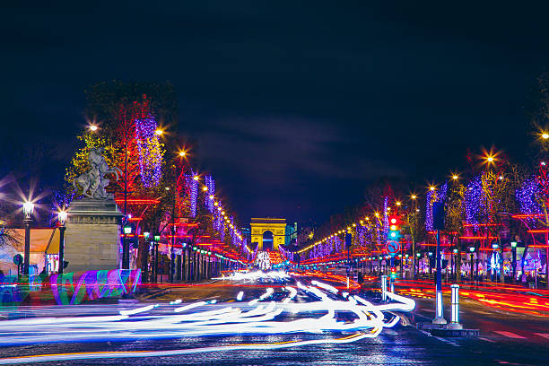 Motion blurred cars on Champs Élysées and Arc de Triomphe with Christmas city lights