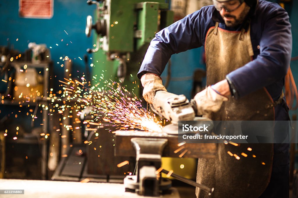 manual worker on a workshop with the grinder Grinding Stock Photo