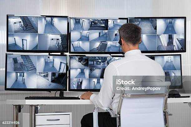 Security System Operator Looking At Cctv Footage At Desk Stock Photo - Download Image Now