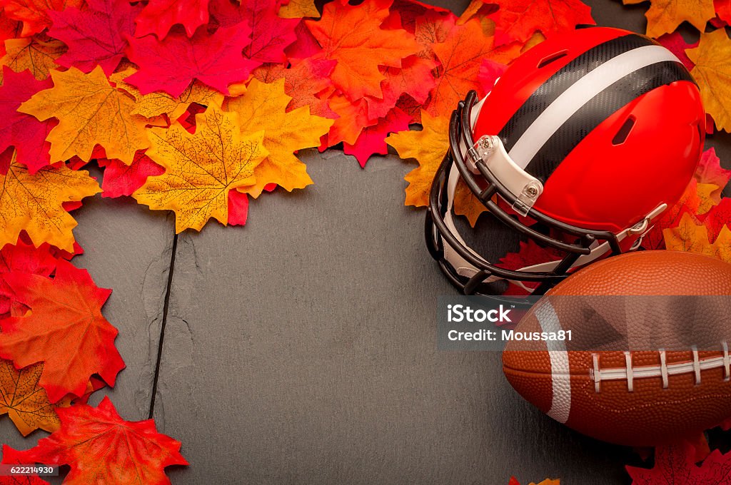 Thanksgiving american football game concept with copyspace Thanksgiving american football game concept with copy space, a generic helmet and ball on the pavement surrounded by fall foliage leafs in autumn Autumn Stock Photo