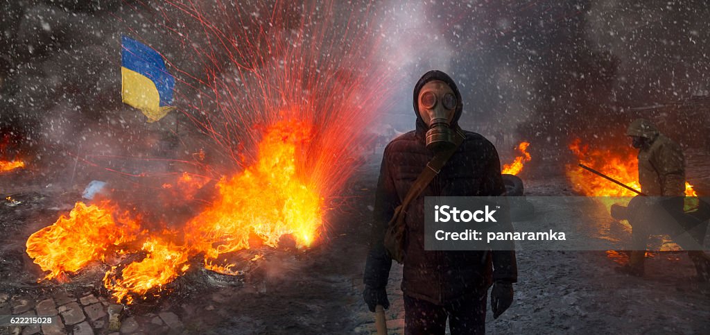 Confronting the government and opposition Radical Protestant in the mask represents the protesters against the authorities among the burning of the capital of the European quarter. Burning rubber tires wheel of fire smoke soot street fighting Ukraine Stock Photo
