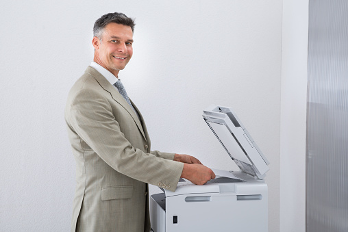 Side view of businessman keeping paper on photocopy machine in office