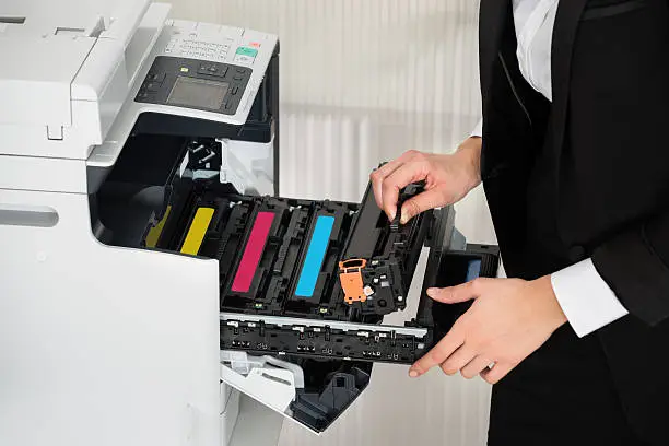 Midsection of young businessman fixing cartridge in printer machine at office