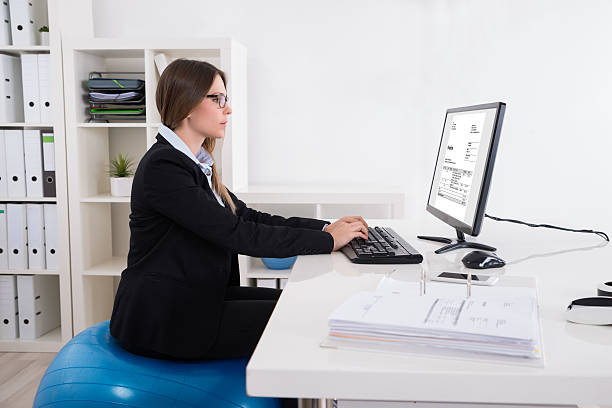 femme d'affaires assis sur ballon de pilates avec ordinateur - photos de fauteuil sphérique photos et images de collection
