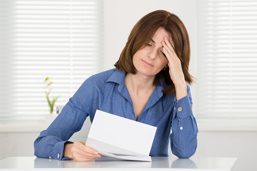 Sad Young Woman Reading Document In Office