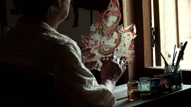 Craftsperson processing thai famous shadow puppet from buffalo leather, handicraft art in the southern region of Thailand (selective focus)