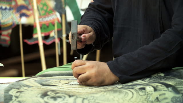 Craftsperson processing thai famous shadow puppet from buffalo leather, handicraft art in the southern region of Thailand (selective focus)