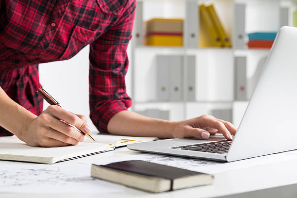 istock Woman in checkered dress typing and writing 622278954